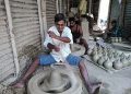 A blind Bappan Paul curving out earthen lamps at his workplace in Srikona