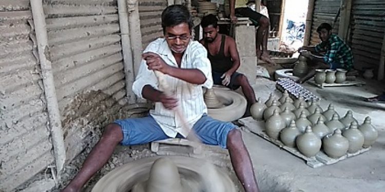 A blind Bappan Paul curving out earthen lamps at his workplace in Srikona