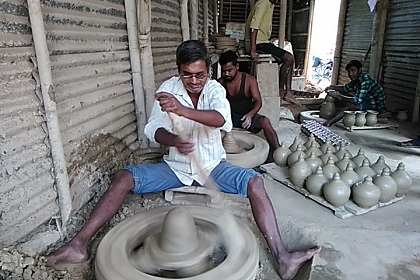 A blind Bappan Paul curving out earthen lamps at his workplace in Srikona