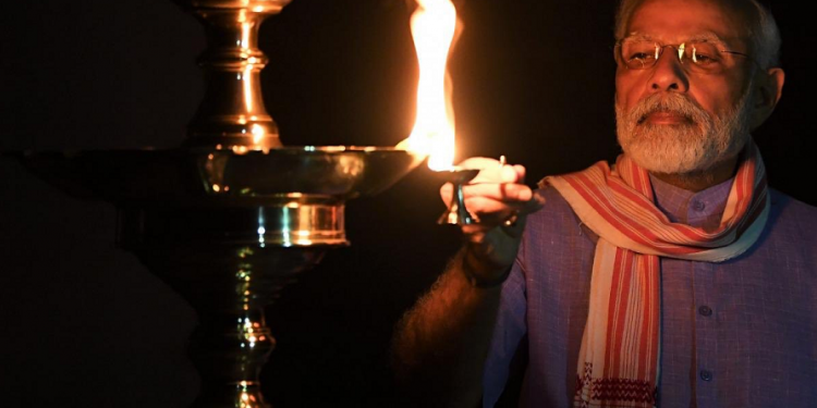 Unity against COVID-19: Wrapping an Assamese Gamocha around his neck PM Modi lights diya for India