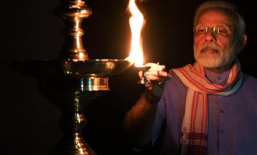 Unity against COVID-19: Wrapping an Assamese Gamocha around his neck PM Modi lights diya for India