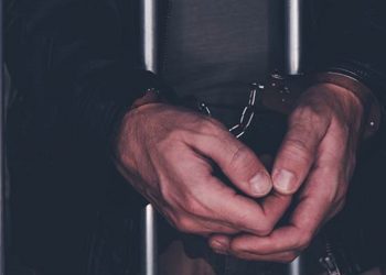 Handcuffed man behind prison bars