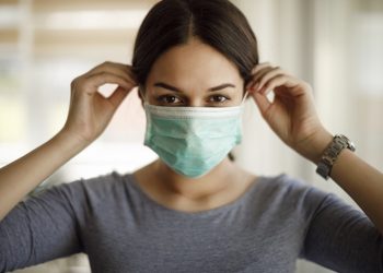 Portrait of young woman putting on a protective mask